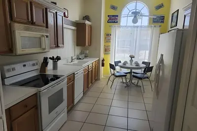 a kitchen with white appliances and a table with chairs at Lake View Pool Home near Disney and Shoppings in Kissimmee