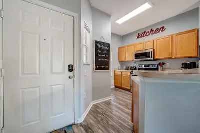 a kitchen with wooden cabinets and a white door at Family Retreat Near Disney in Emerald Island in Kissimmee