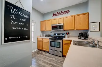 a kitchen with wooden cabinets and a blackboard on the wall at Family Retreat Near Disney in Emerald Island in Kissimmee