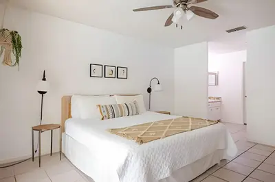 a white bedroom with a bed and a ceiling fan at 10 Minutes to Disney Pool Home *Renovated* in Kissimmee