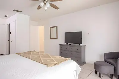 a bedroom with a bed and a tv and a chair at 10 Minutes to Disney Pool Home *Renovated* in Kissimmee