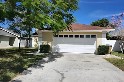 a house with a white garage and a driveway at Lakeside Pool Home, Games close to Disney & Malls in Kissimmee