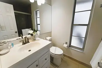 a bathroom with a sink and a toilet and a mirror at Lakeside Pool Home, Games close to Disney & Malls in Kissimmee
