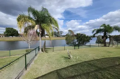 a fence with palm trees next to a lake at Lakeside Pool Home, Games close to Disney & Malls in Kissimmee