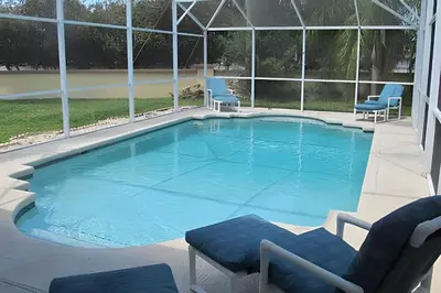 a large swimming pool with two chairs at 10 Minutes to Disney! Pool Home Large Lot in Kissimmee