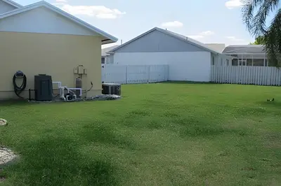 a yard with two white buildings and a green lawn at 10 Minutes to Disney! Pool Home Large Lot in Kissimmee
