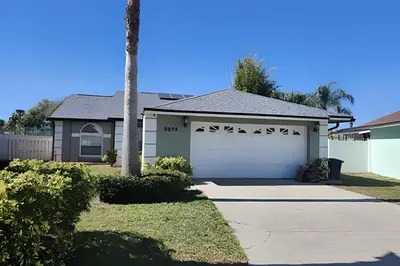 a house with a garage and a palm tree at 10 Minutes to Disney! Pool Hom, Large Backyard in Kissimmee