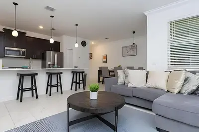 a living room and kitchen with a couch and a table at Luxurious Home w/ Pool Near Disney in Kissimmee