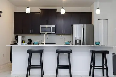 a kitchen with a counter with stools and a refrigerator at Luxurious Home w/ Pool Near Disney in Kissimmee
