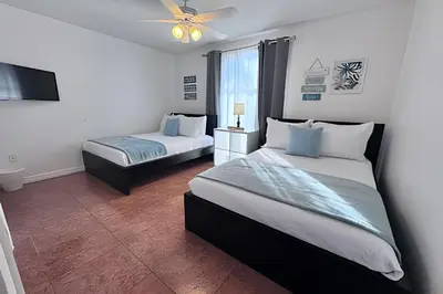 a bedroom with two beds and a flat screen tv at Corner Lot Pool Home Central Located near Disney in Kissimmee