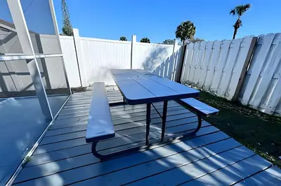 a blue picnic table on a deck with a fence at Corner Lot Pool Home Central Located near Disney in Kissimmee
