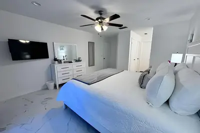 a white bedroom with a bed with a ceiling fan at Corner Lot Pool Home Central Located near Disney in Kissimmee