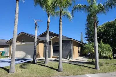 a group of palm trees in front of a house at Corner Lot Pool Home Central Located near Disney in Kissimmee
