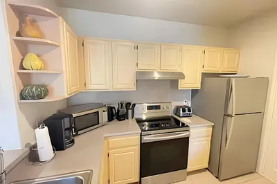 a small kitchen with white cabinets and appliances at Cozy & Bright Condo in Legacy Dunes near Disney in Kissimmee