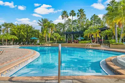 a swimming pool with palm trees in the background at Beautiful Epic Universe Condo, Vista Cay - 1004 in Orlando