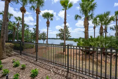 a fence with palm trees and water in the background at Beautiful Lakeview Condo, New Listing -1024 in Orlando