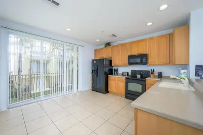 a kitchen with wooden cabinets and a black refrigerator at Beautiful Townhome, Vista Cay Resort Direct - 4010 in Orlando