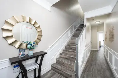 a hallway with a staircase with a mirror and a table at Beautiful Family Townhome, Near The Parks - 4032 in Orlando