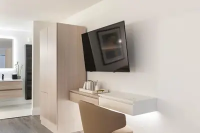 a white room with a desk and a tv on a wall at The Vietta Hotel in Kissimmee