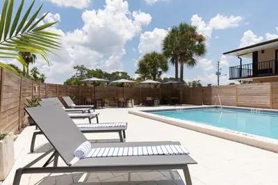 a swimming pool with lounge chairs next to a building at The Vietta Hotel in Kissimmee