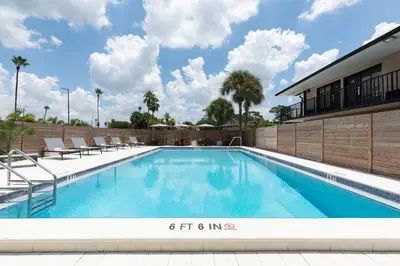 a swimming pool with chairs and a building at The Vietta Hotel in Kissimmee