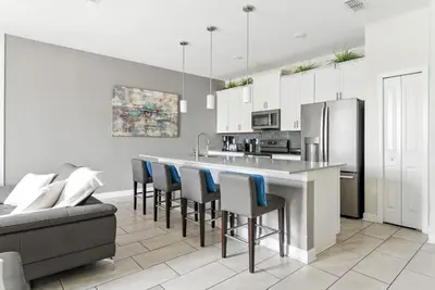 a kitchen with a bar with chairs and a refrigerator at Relax Near Disney 4BR Home with Pool in Kissimmee