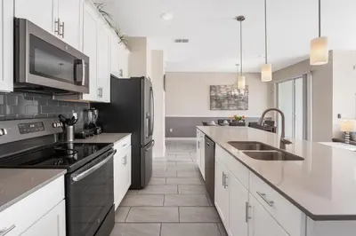 a kitchen with white cabinets and a black refrigerator at Relax Near Disney 4BR Home with Pool in Kissimmee