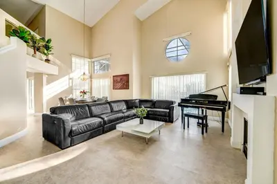 a living room with a black leather couch and a piano at Bay Pointe Pool Home Near Parks in Kissimmee