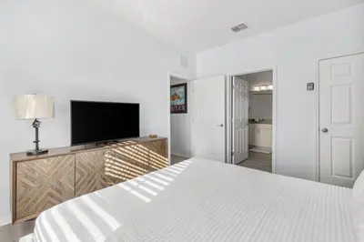 a white bedroom with a bed and a flat screen tv at 4BR Themed Home W Resort Pool Near Disney in Kissimmee