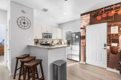a kitchen with a counter with stools and a refrigerator at 4BR Themed Home W Resort Pool Near Disney in Kissimmee