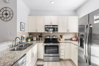 a kitchen with white cabinets and stainless steel appliances at 4BR Themed Home W Resort Pool Near Disney in Kissimmee