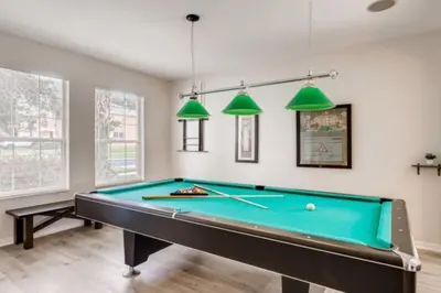 a pool table in a living room with lights at Lakefront 6BR Resort Pool Home Near Disney World in Kissimmee