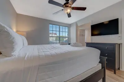 a bedroom with a white bed with a ceiling fan at Charming and Cozy Townhome Near Disney in Kissimmee