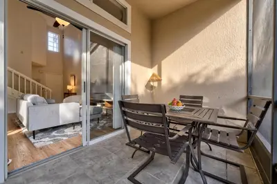 a balcony with a table and chairs and a living room at Charming and Cozy Townhome Near Disney in Kissimmee
