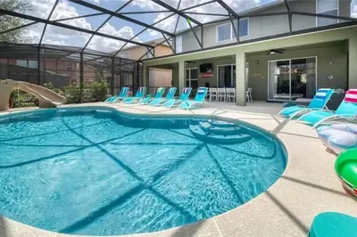 a large swimming pool with chairs and a house at The Minions Mansion 6br Resort Pool Home By Disney in Kissimmee