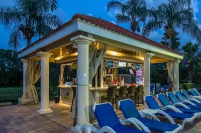 a bar with blue chairs in front of a gazebo at The Minions Mansion 6br Resort Pool Home By Disney in Kissimmee