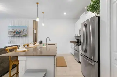 a kitchen with a stainless steel refrigerator and a table at 2645 Casa Luxuosa com Piscina Privativa perto da Disney in Kissimmee