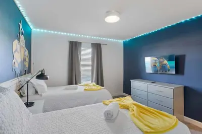 a bedroom with two beds and a blue wall at 2645 Casa Luxuosa com Piscina Privativa perto da Disney in Kissimmee