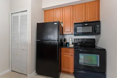 a kitchen with black appliances and wooden cabinets at Cozy Apartment w Kitchen Near Universal in Orlando