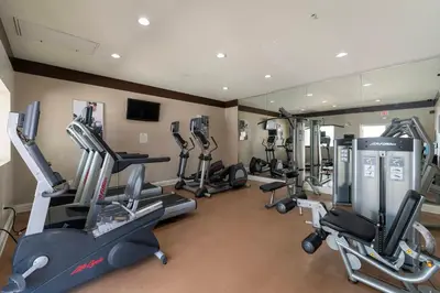 a gym with several tread machines and a mirror at Combined units 2 Kitchens Sleeps 6 in Orlando