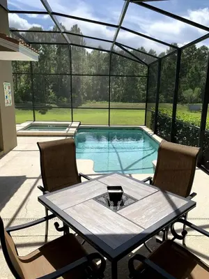 a patio with a table and chairs and a swimming pool at Relaxing Villa very close to Disney and Universal in Kissimmee