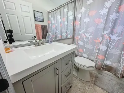 a bathroom with a sink and a toilet and a shower curtain at Sunny Oaks Poolside, pool spa games,4m to Disney in Orlando