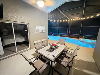 a dining room with a table and chairs and a swimming pool at Sunny Oaks Poolside, pool spa games,4m to Disney in Orlando