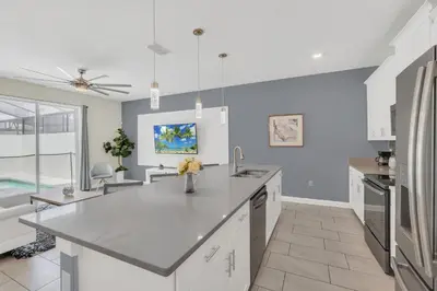 a kitchen with white cabinets and a large island at Storey Lake Escape with Pool in Kissimmee