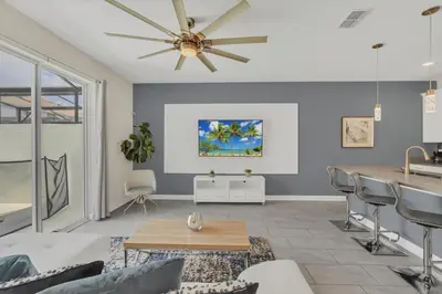 a living room with a ceiling fan and a table at Storey Lake Escape with Pool in Kissimmee
