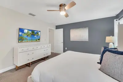 a bedroom with a white bed and a white dresser at Storey Lake Escape with Pool in Kissimmee