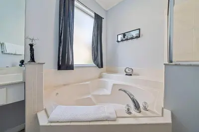 a white bathroom with a tub and a window at 7 Bed Family Villa for All in Kissimmee