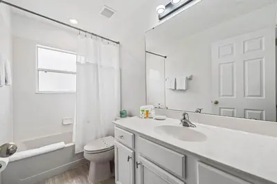 a bathroom with a sink and a toilet and a mirror at 7 Bed Family Villa for All in Kissimmee