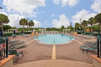 a large swimming pool in a park with chairs at 4 Bedroom 3 Bathroom Villas At SevenDwarfs 4-108 in Kissimmee