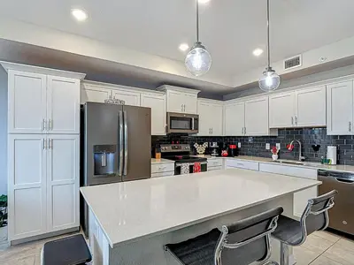 a kitchen with white cabinets and a stainless steel refrigerator at Storey Lake Beautiful 2-BR Condo, Resort Amenities in Kissimmee